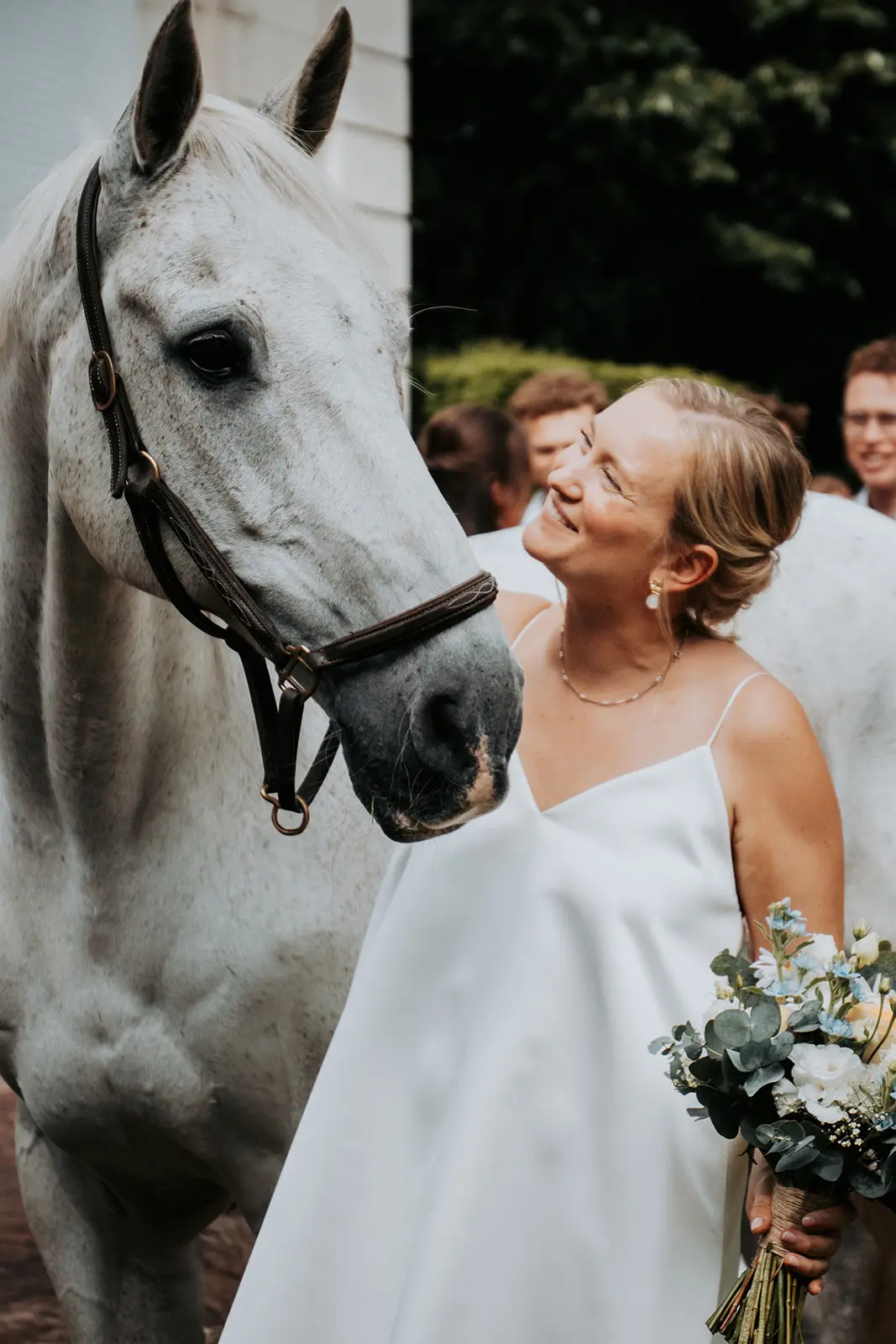 Bruid met bruidsboeket naast een wit paard