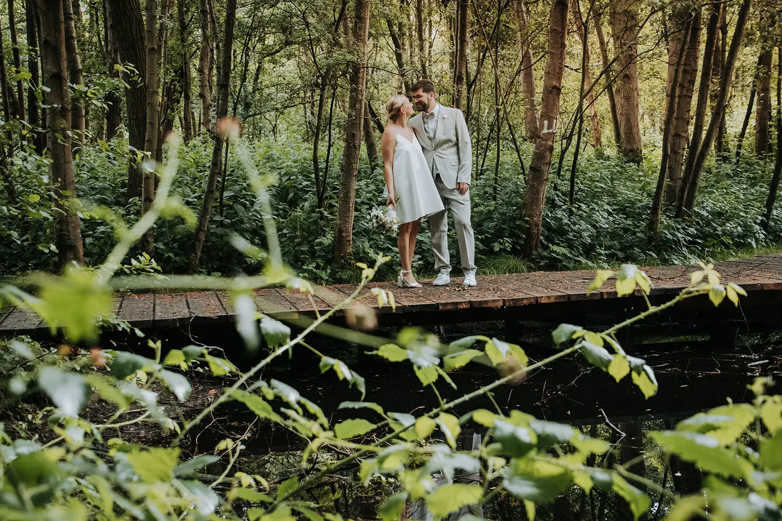 Bruidspaar op een houten brug in het bos